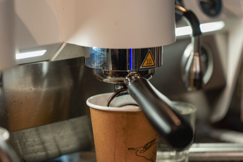 Espresso brewing into a paper cup under the portafilter at Crane Coffee